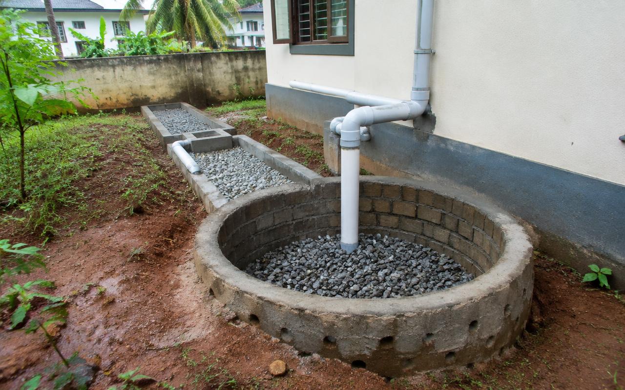 Rainwater harvesting recharge pit with filter beds beside a building